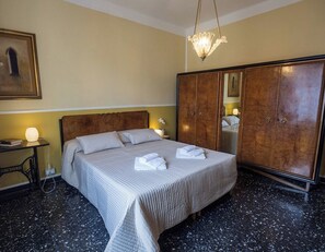 A hotel room with a bed, a wardrobe, a desk, and a nightstand.