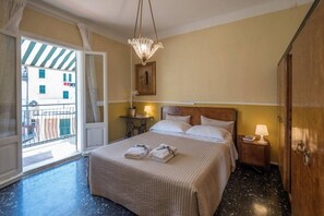 Una habitación de hotel con cama, mesita de noche, lámpara y vistas al balcón exterior.