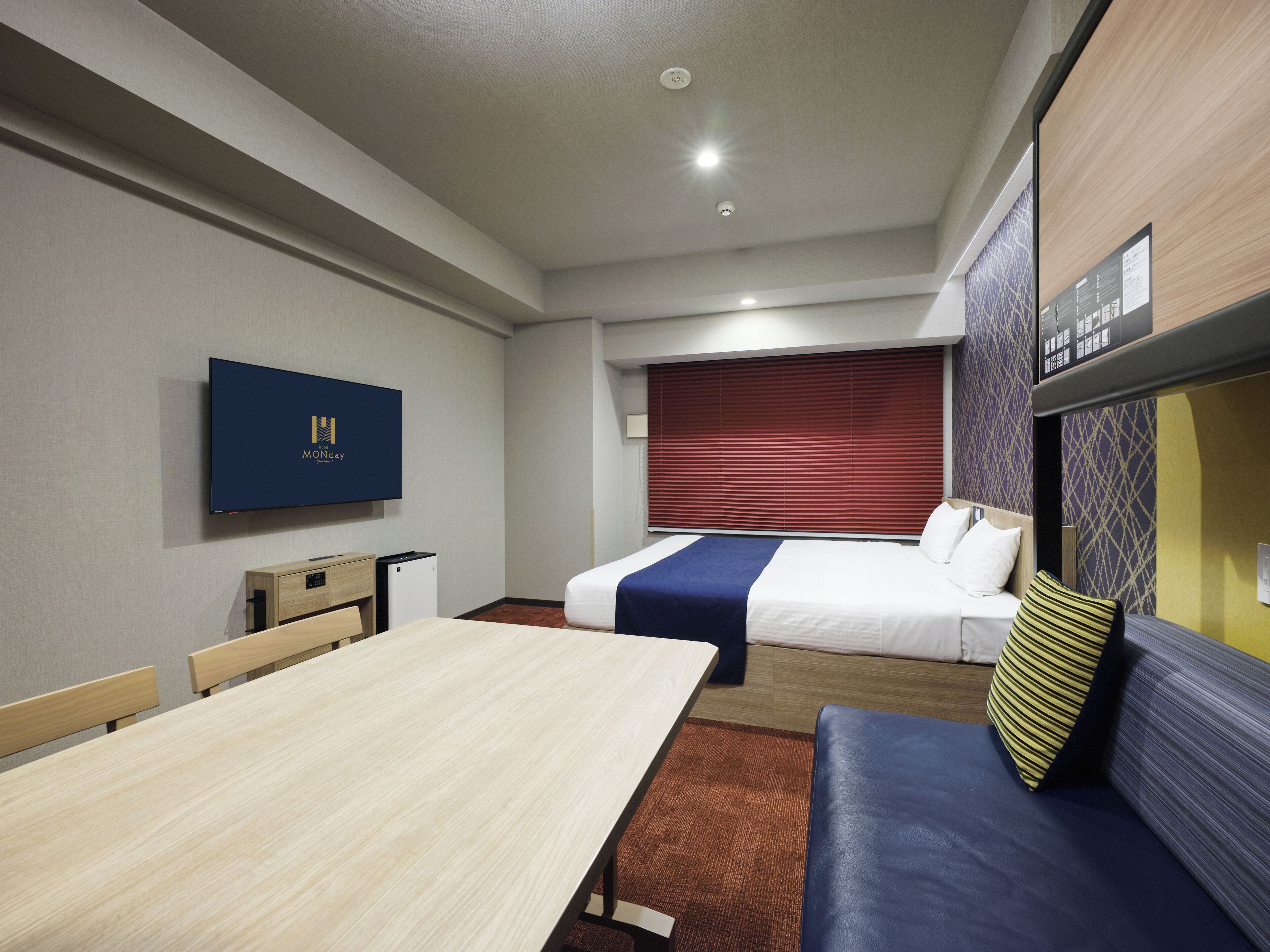 A hotel room with a bed, a sofa, a TV, and a desk.