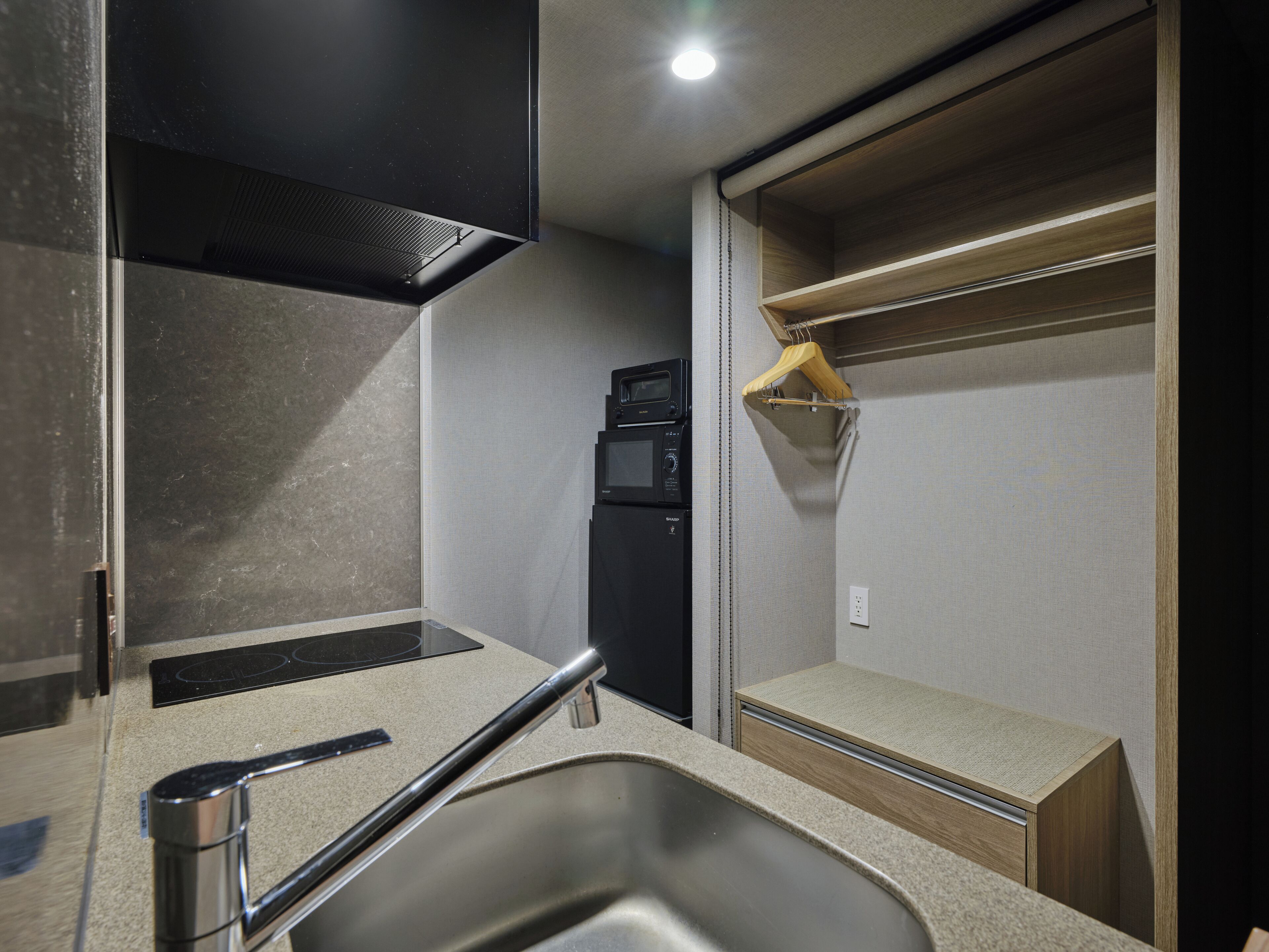 A compact kitchenette with a stainless steel sink, a microwave, and a small refrigerator.