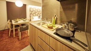 Una cucina moderna con zona pranzo, mobili in legno, piano cottura integrato e un'ampia finestra con persiane.