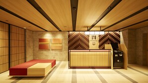 Una hall d'hotel moderna con una reception, una zona salotto e un muro con listelli di legno verticali.