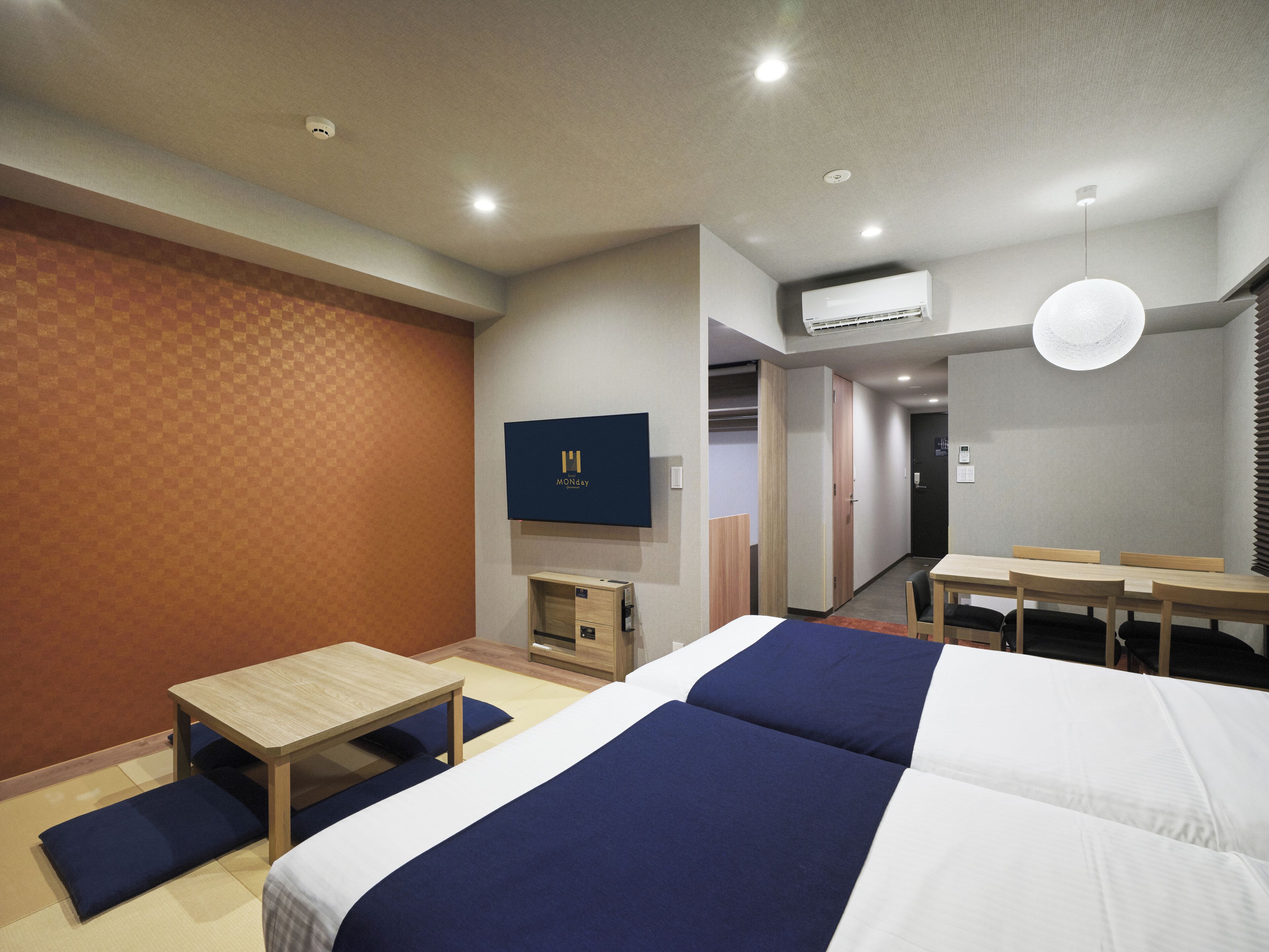 A hotel room with a large bed, a desk, and a TV on the wall.