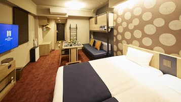 A hotel room with a large bed, a desk with a chair, a small table, and a TV on the wall.