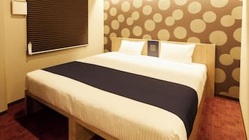 Habitación de hotel con cama, mesita de noche, luz empotrada en la pared y papel tapiz estampado.