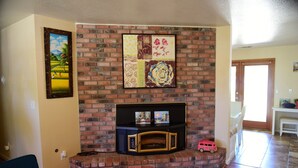 A living room with a brick fireplace, a small table with a toy car, and a painting on the wall. - Charming Family House Near Sequoia Park (Visalia)