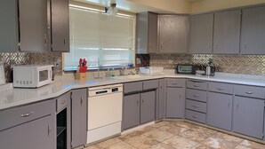 A kitchen with grey cabinets, a white microwave, a toaster, and a sink. - Charming Family House Near Sequoia Park (Visalia)