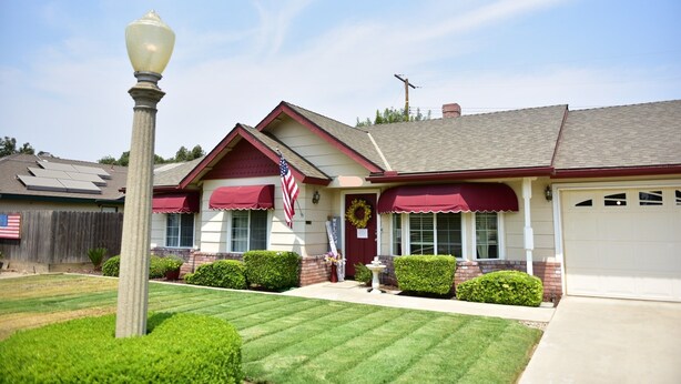 A house with a red awning, a garage, and a well-maintained lawn. - Charming Family House Near Sequoia Park (Visalia)