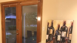 A room with a glass-top desk, a white chair, and a wall-mounted artwork of wine bottles. - Charming Family House Near Sequoia Park (Visalia)