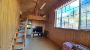 A wooden interior with a loft bedroom, a kitchen area, and a large window offering a view of the outdoors. - Ulleung Haeoreum Pension (Ulleung)