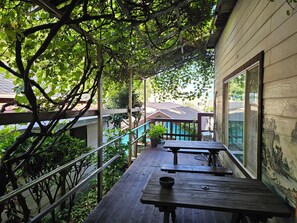 A wooden deck with picnic tables and a railing, overlooking a residential area with houses and a swimming pool. - Ulleung Haeoreum Pension (Ulleung)