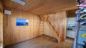 A wooden interior with a wooden staircase, a kitchen area, and a framed picture on the wall. - Ulleung Haeoreum Pension (Ulleung)