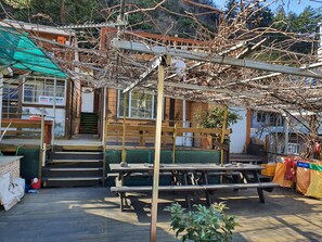 Eine Holzterrasse mit Picknicktischen und einem überdachten Sitzbereich.