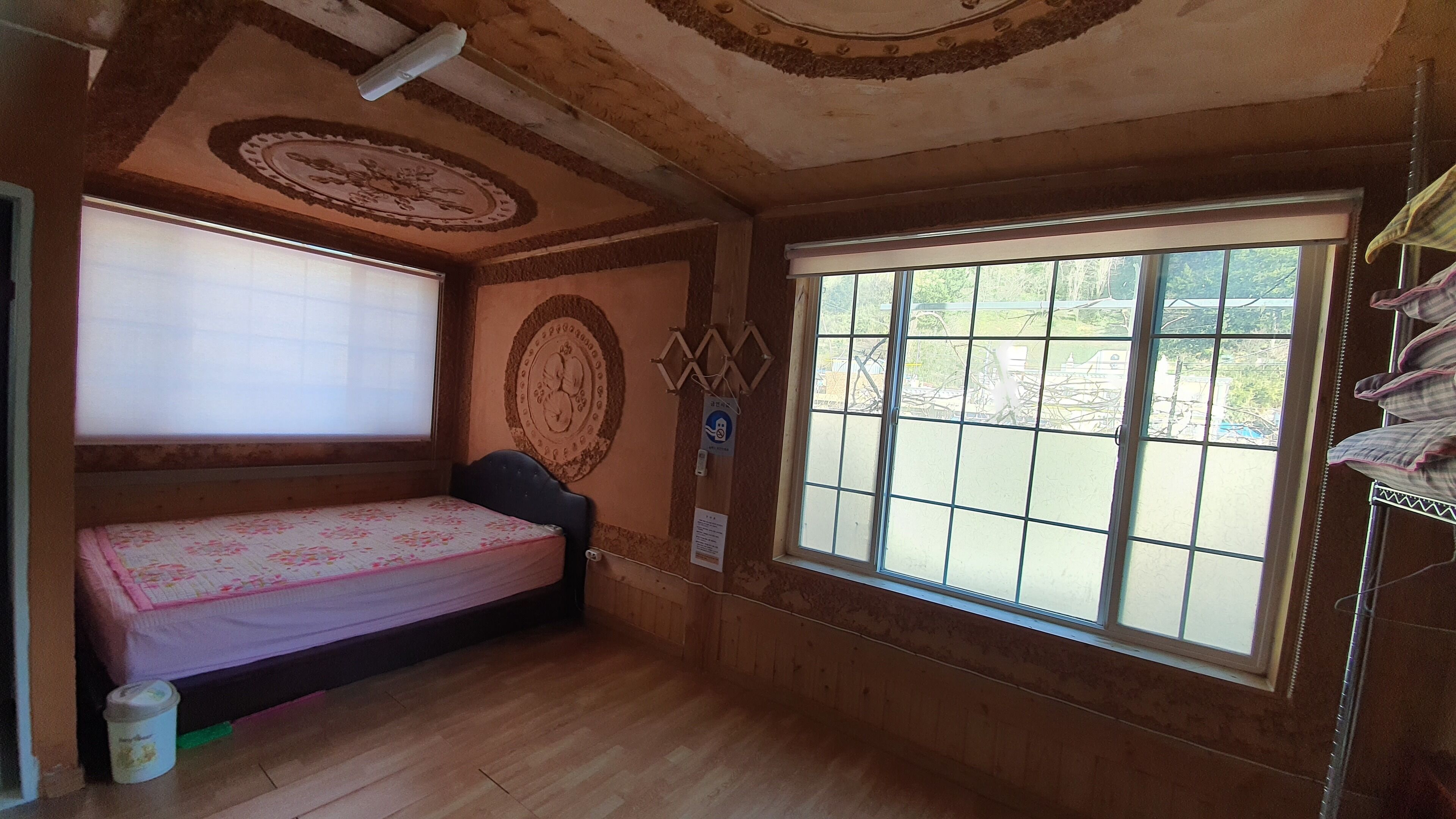 Una habitación pequeña con una cama individual, una ventana con vistas y diseños decorativos en el techo.
