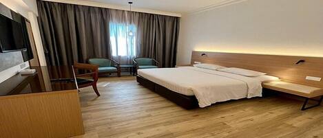 A hotel room with a bed, a desk, and two chairs.