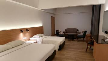 A hotel room with two beds, a sofa, a chair, a small table, and a TV.