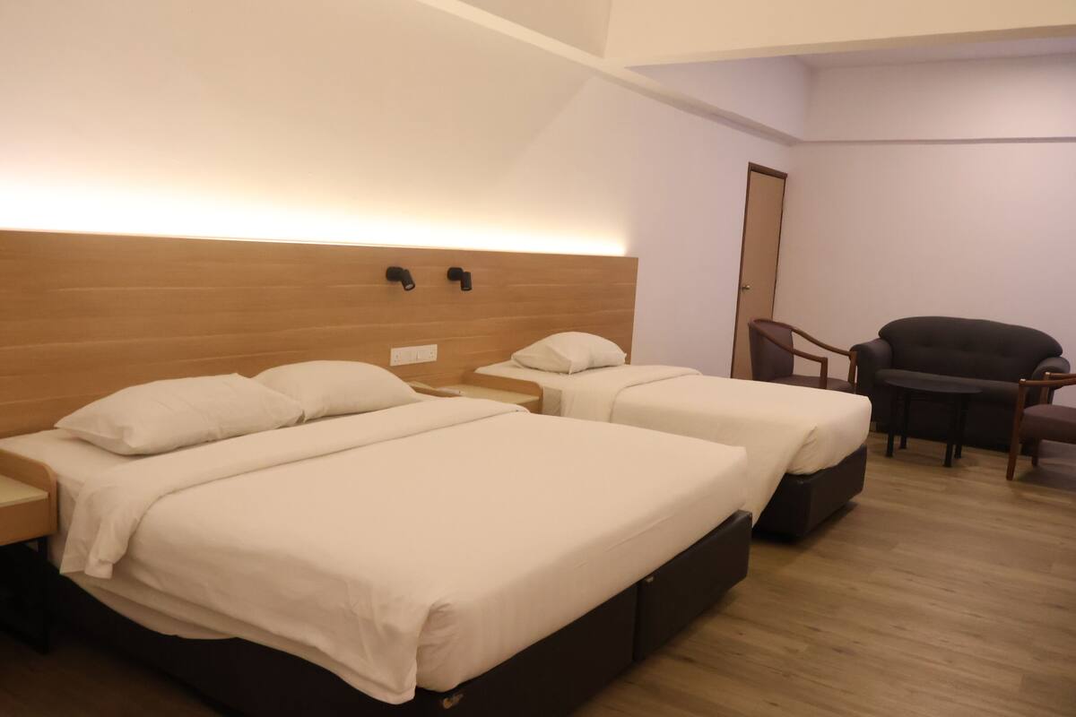 A hotel room with two beds, a wooden headboard, a small table, and a chair.