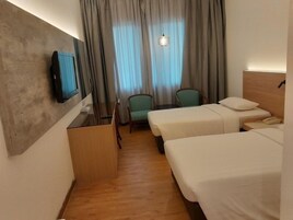 Habitación de hotel con dos camas, televisión, escritorio y una silla.