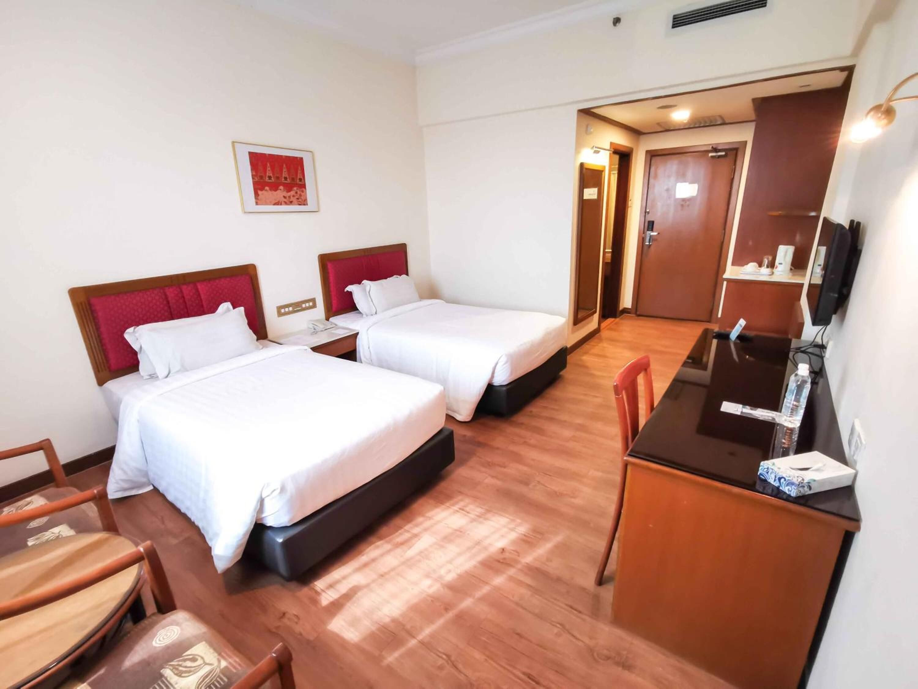 Habitación de hotel con dos camas, un escritorio, una silla y un televisor.