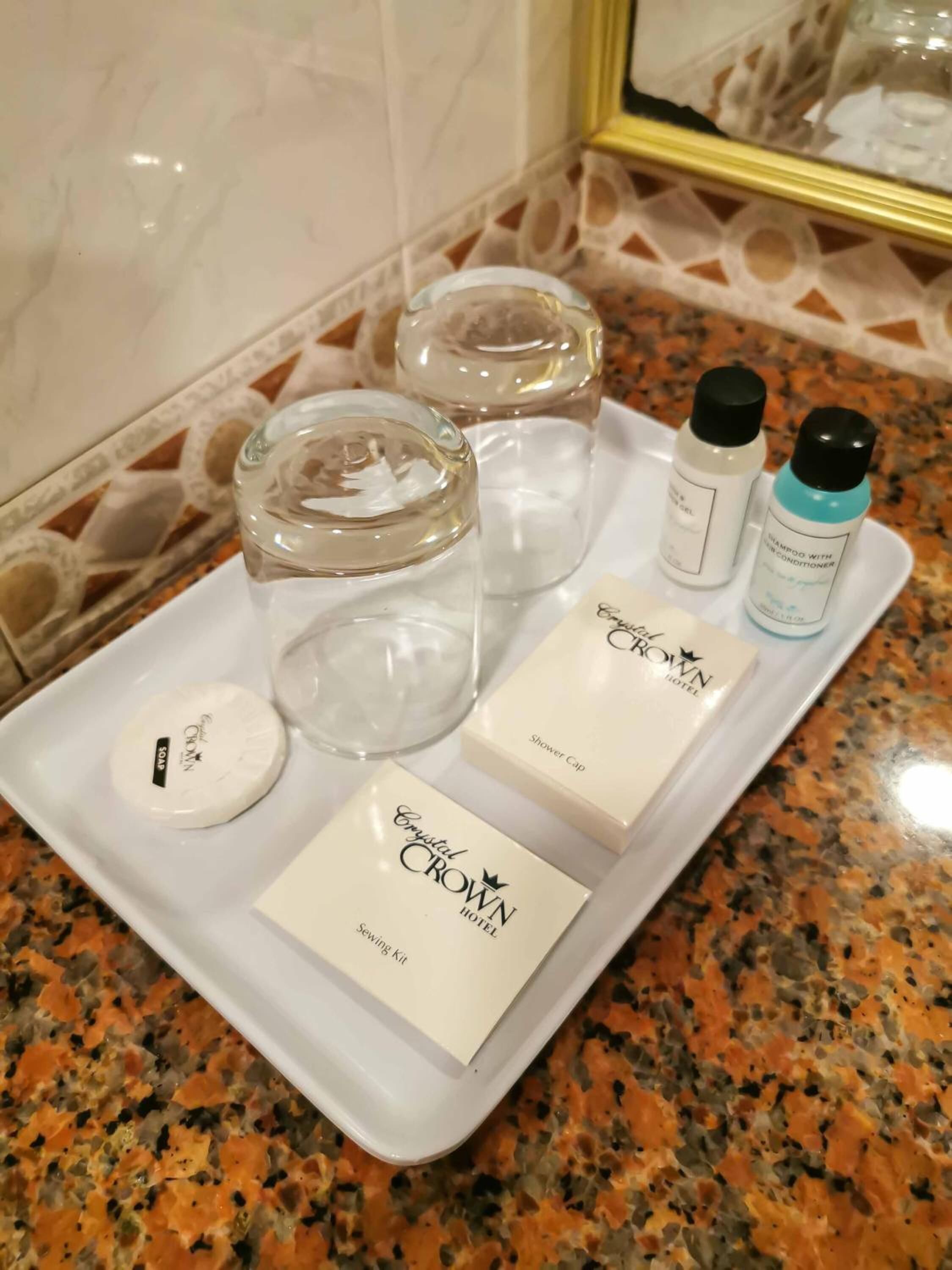 A tray with toiletries including a shower cap, soap, shampoo, and a sewing kit.