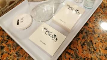 A tray with toiletries including a shower cap, soap, shampoo, and a sewing kit.