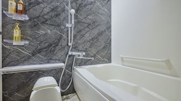 Un baño con pared de mármol, bañera, ducha y estantes con artículos de aseo.