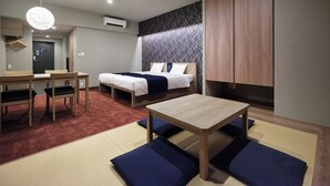 Ein modernes Hotelzimmer mit einem Bett, einem Schreibtisch und einer Sitzecke mit Kissen.