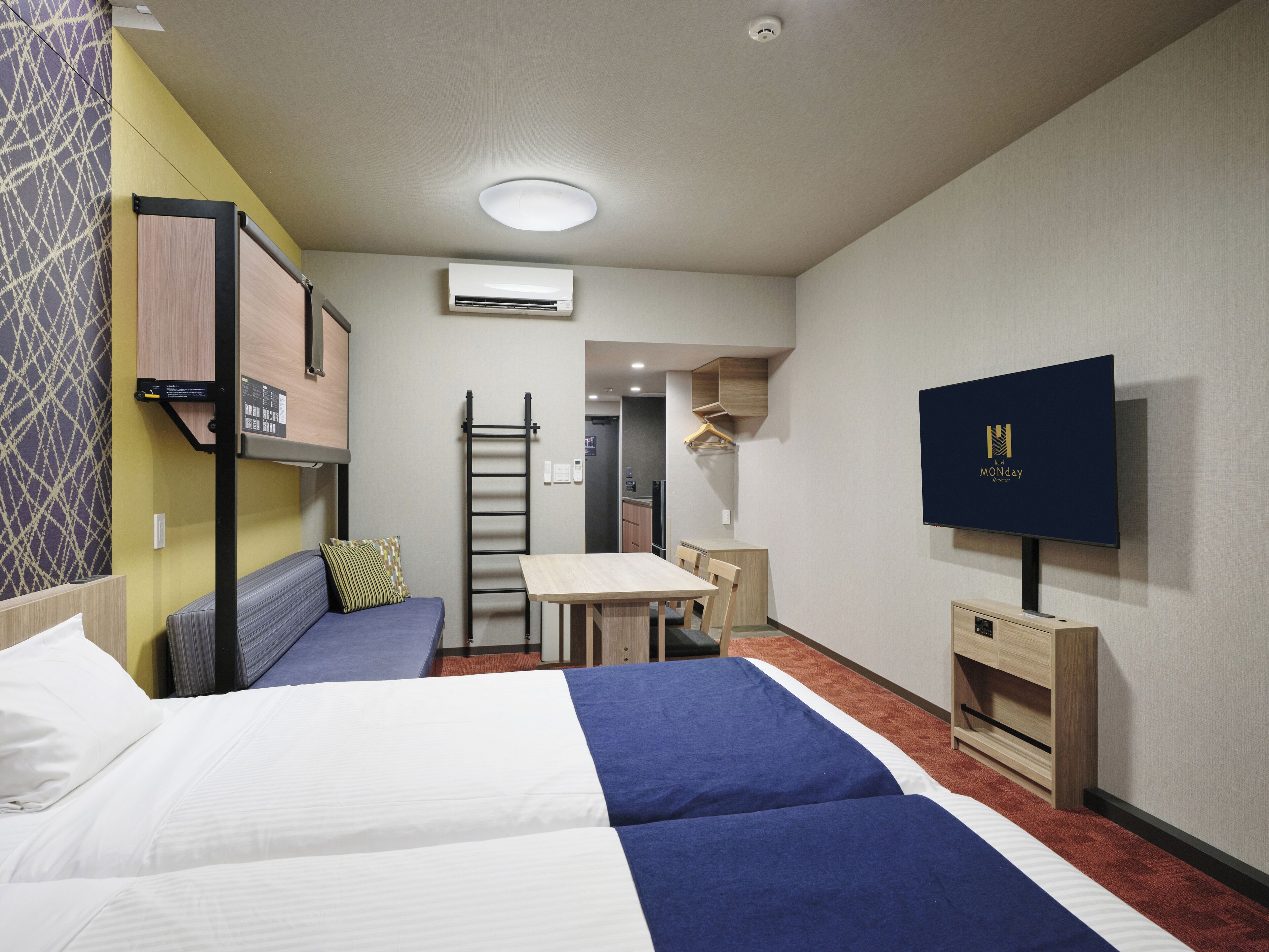 A hotel room with two beds, a desk, a TV, and a wardrobe.