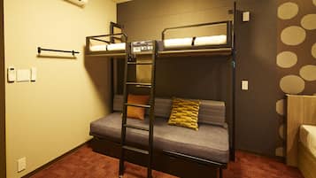 Une chambre avec un lit superposé, une échelle, un canapé et un mur décoré de motifs.