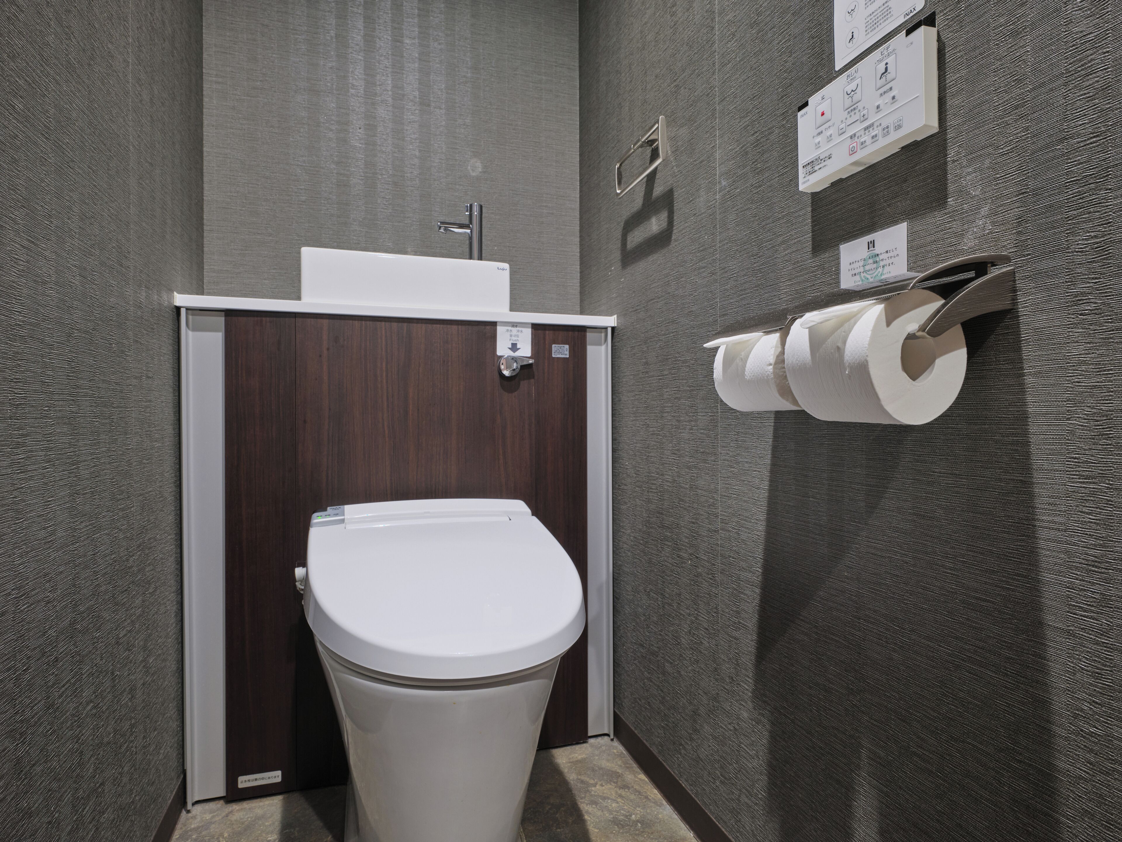Een kleine badkamer met een wit toilet, een wastafel en een papieren handdoekdispenser.