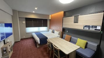 Habitación de hotel pequeña con cama, escritorio, mesita y sofá.