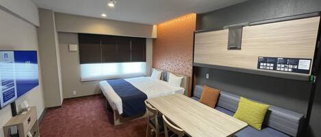 Habitación de hotel pequeña con cama, escritorio, mesita y sofá.