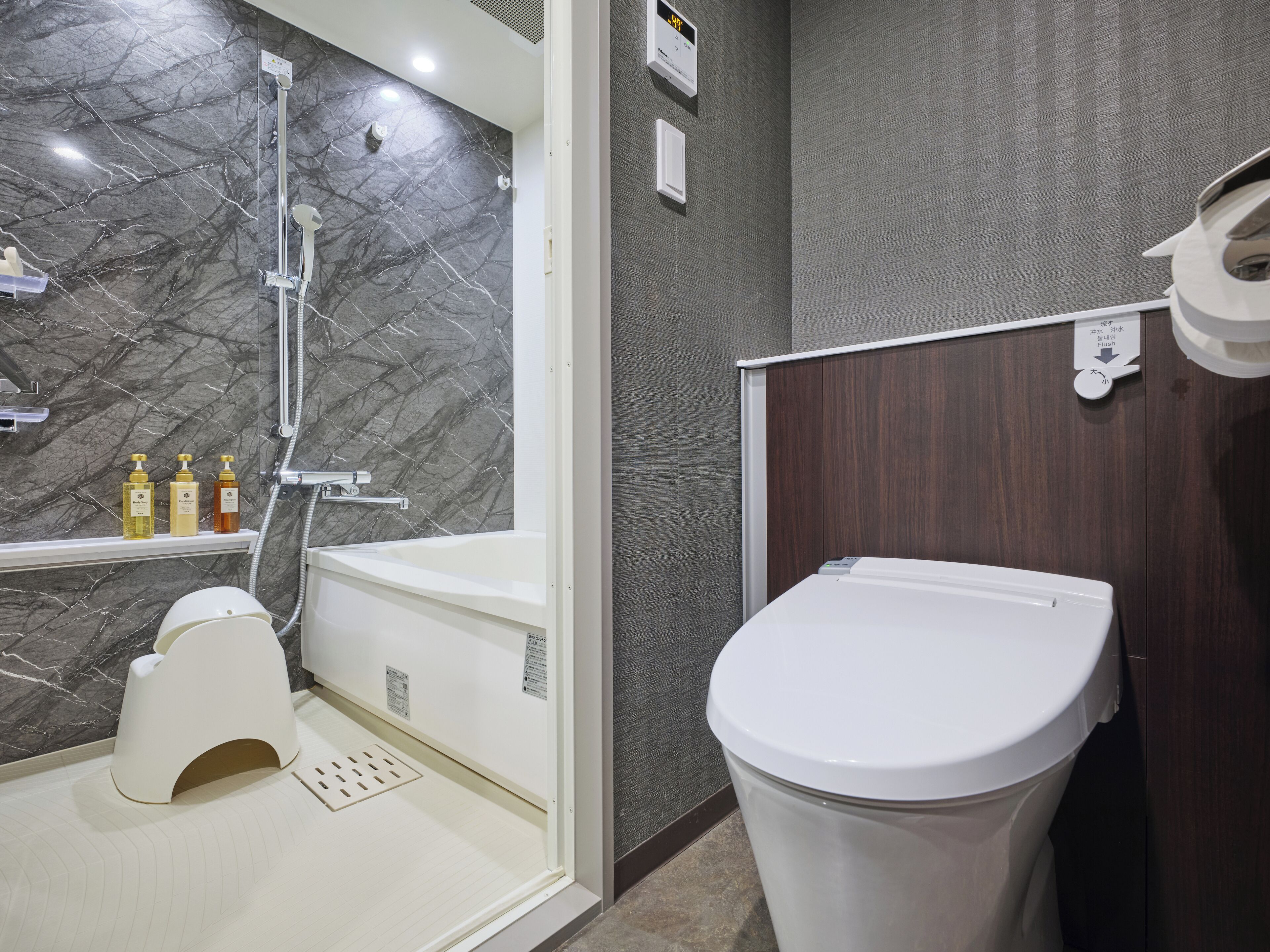 A modern bathroom with a marble shower, a toilet, and a sink.