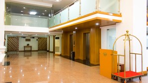 A hotel lobby with a polished floor, a reception desk, a luggage cart, and a glass railing on the upper level. - Lin Unity Win Hotel (Yangon)