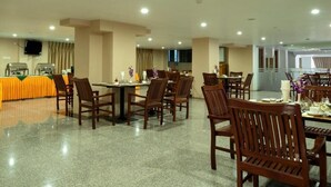 A spacious dining area with multiple tables and chairs, a buffet setup, and a television screen on the wall. - Lin Unity Win Hotel (Yangon)