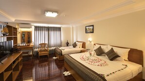 A hotel room with two beds, a desk, a chair, a TV, and a wardrobe. - Lin Unity Win Hotel (Yangon)