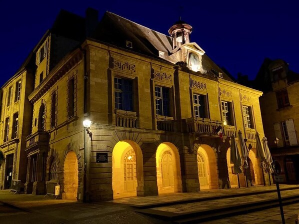 A historic building with arched windows and a clock tower, illuminated at night.