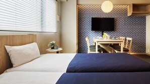 Una camera d'albergo con un letto, una scrivania e una televisione appesa al muro.