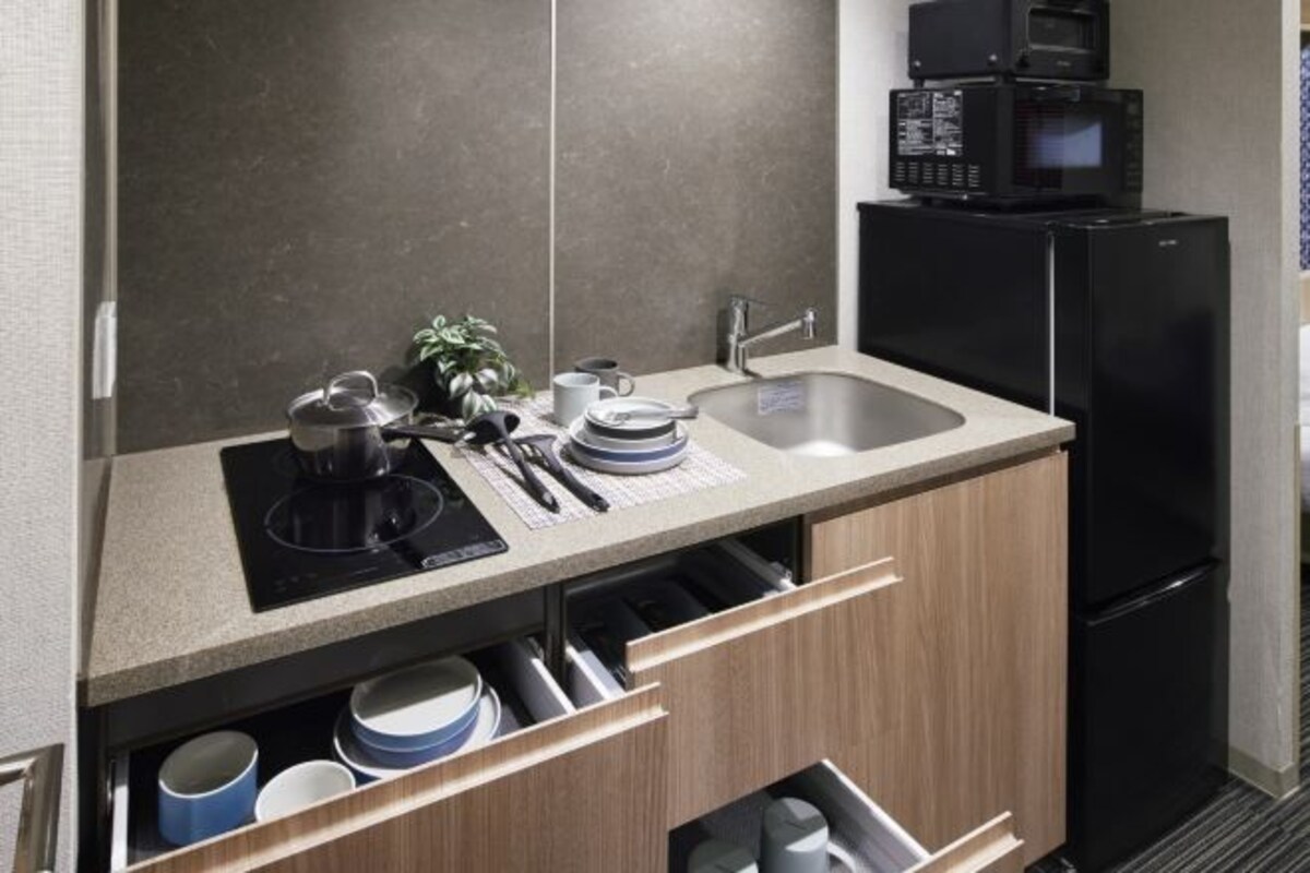 A modern kitchen with a built-in microwave, sink, and a coffee maker.