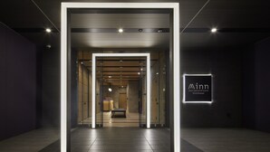 Ingresso moderno di un hotel dal design minimalista, con una porta in vetro, una panca e una targa con il nome dell'hotel.