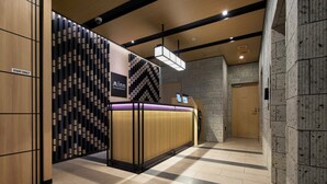 Una moderna hall d'hotel con una reception, un cartello con la scritta 'Solo personale' e il logo 'Minn your second home'.