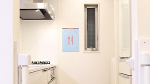 Ett kompakt kök med vita vitvaror, en rostfri köksfläkt och ett fönster med utsikt.
