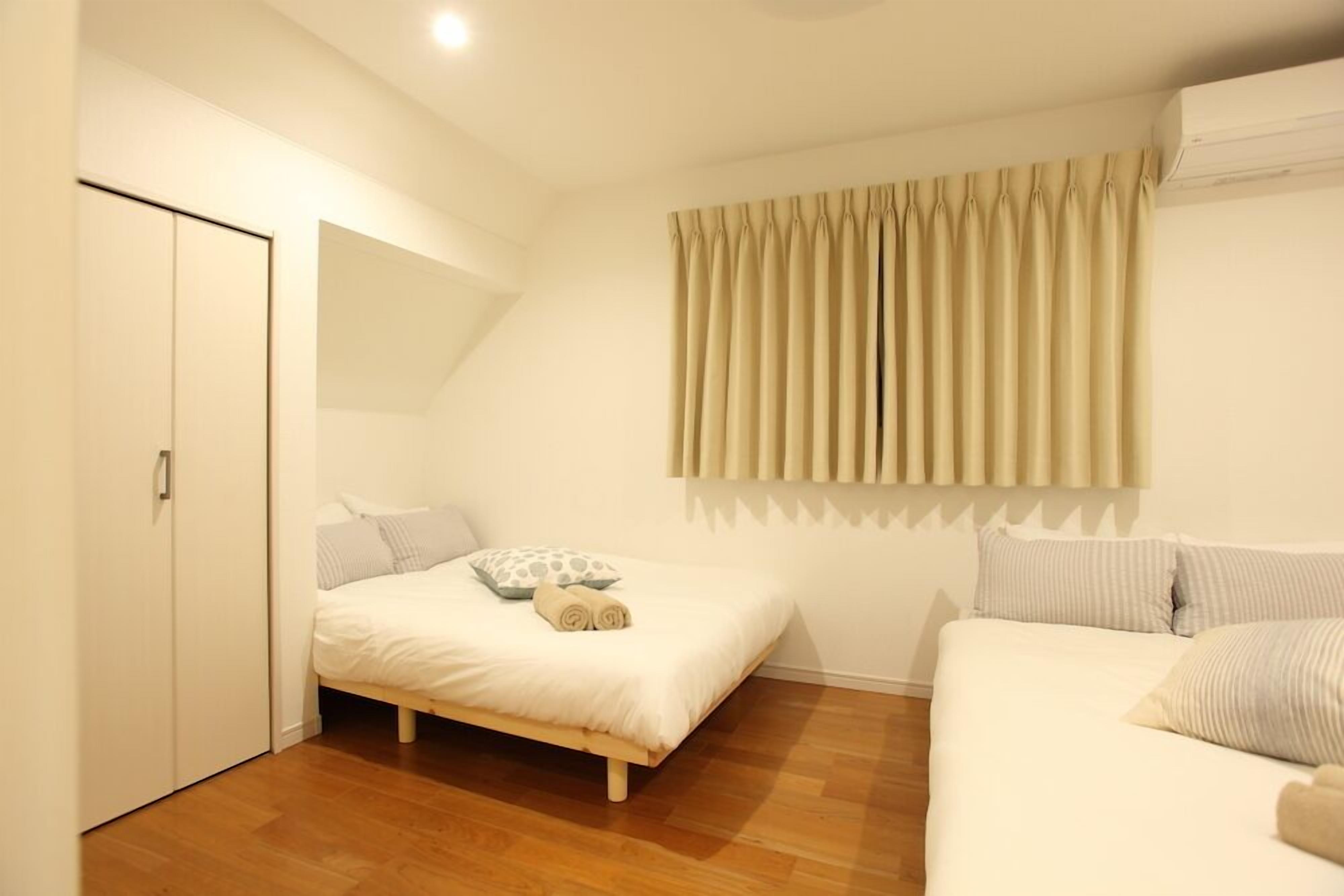 A bedroom with a bed, a wardrobe, and a window with curtains.