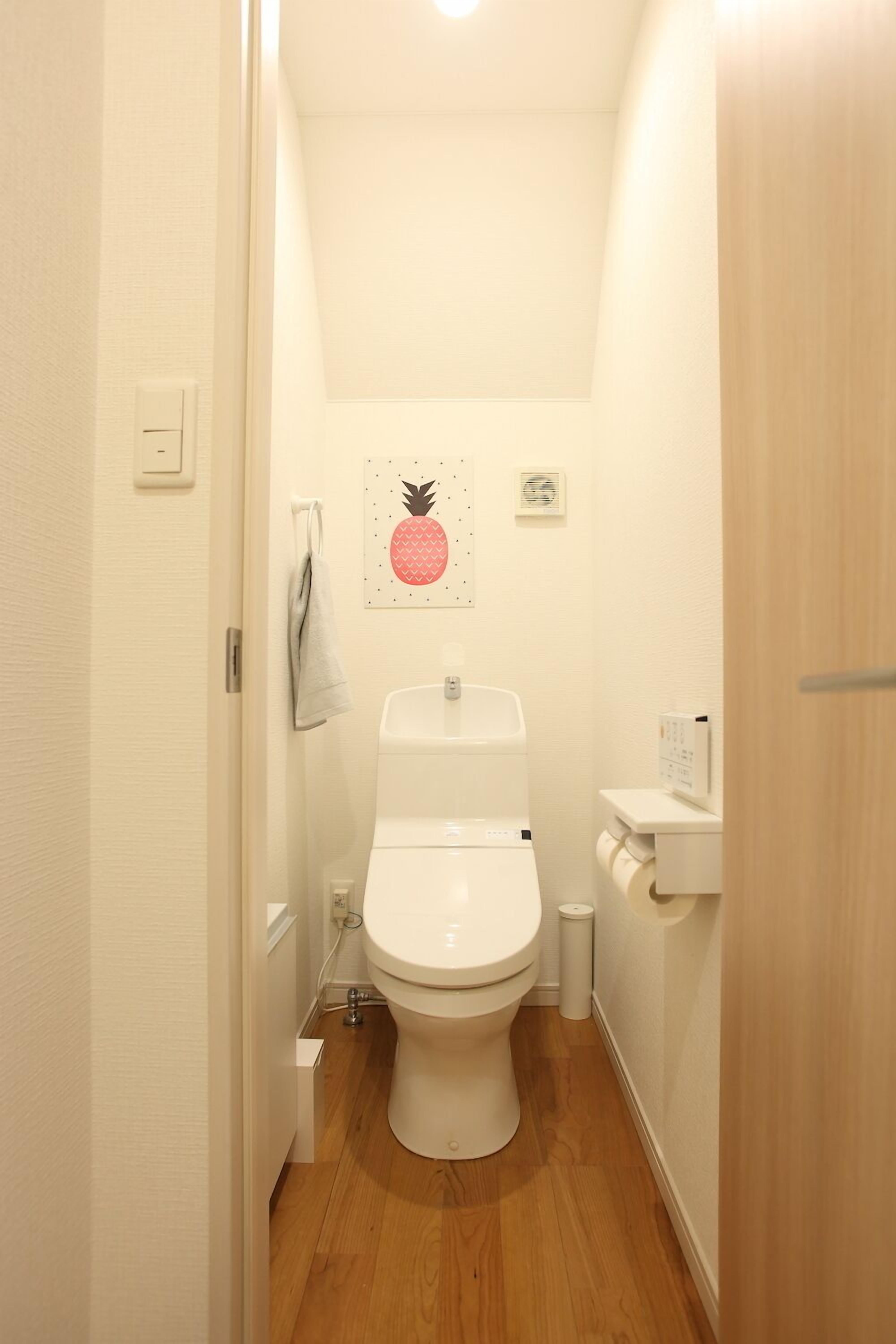A small, narrow bathroom with a toilet, a sink, and a wall-mounted toilet paper holder.