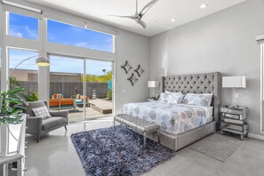Une chambre moderne avec un grand lit, un canapé gris et un tapis bleu.