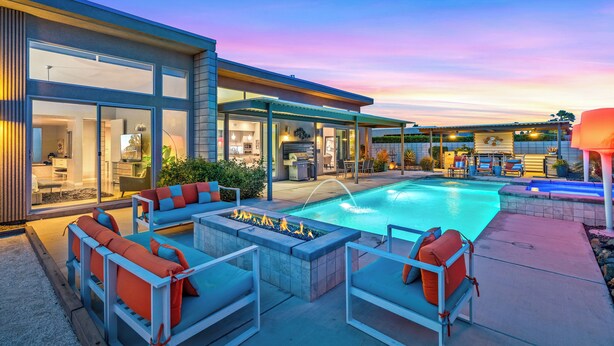 Ein modernes Haus mit Swimmingpool, Sitzgelegenheiten im Freien und einer überdachten Terrasse.