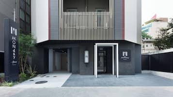 A modern building with a flat facade, a balcony with vertical slats, and a sign reading "MONDAY part".