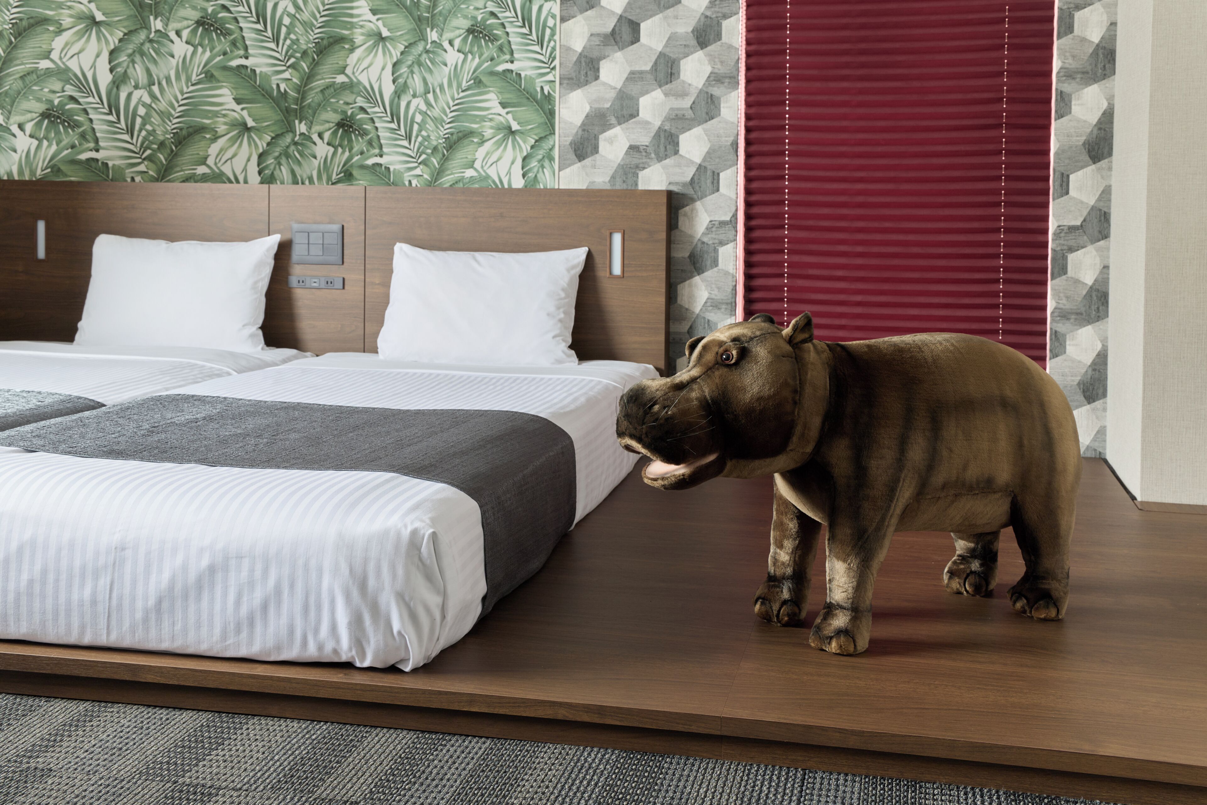 A hotel room with a bed, a control panel, and a large animal statue.