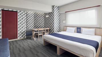 A hotel room with a bed, a desk, and a chair.