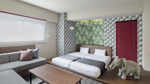 A modern hotel room with a sofa, two beds, a small elephant decoration, and patterned walls. - MONday Apart Hamamatsucho Daimon (Tokyo)